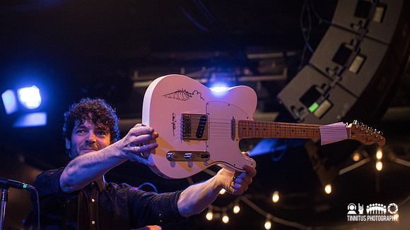 Will Dailey holding a guitar autographed by Eddie Vedder, up for